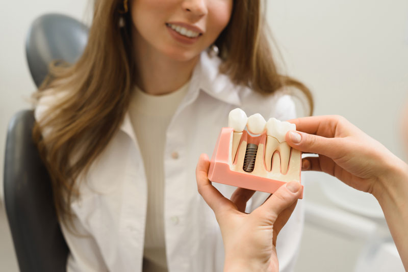 Dental Patient Getting Shown A Dental Implant Model During Her Consultation in Plymouth, MA
