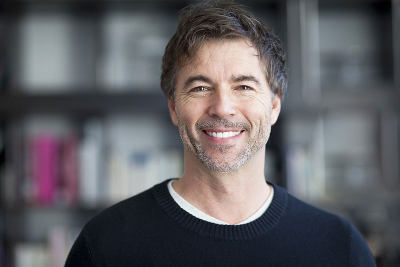 a patient smiling after receiving hair restoration from an oral surgeon