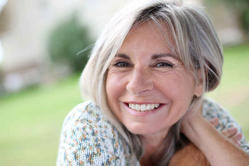 a dental patient outside smiling because she has false teeth