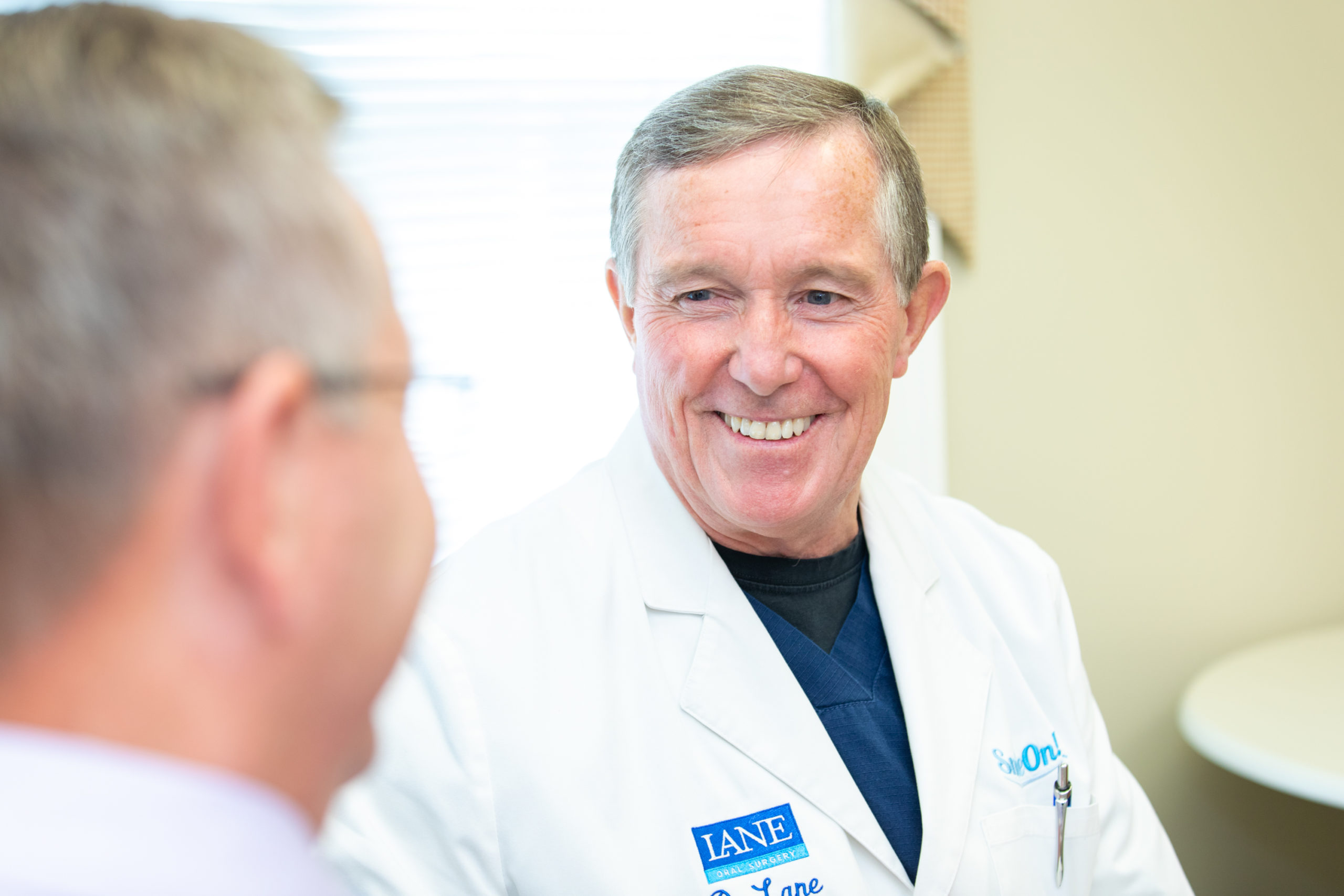 doctor lane with a smile on dental implant procedure patient in a consultation.