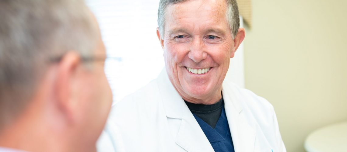 doctor lane with a smile on dental implant procedure patient in a consultation.