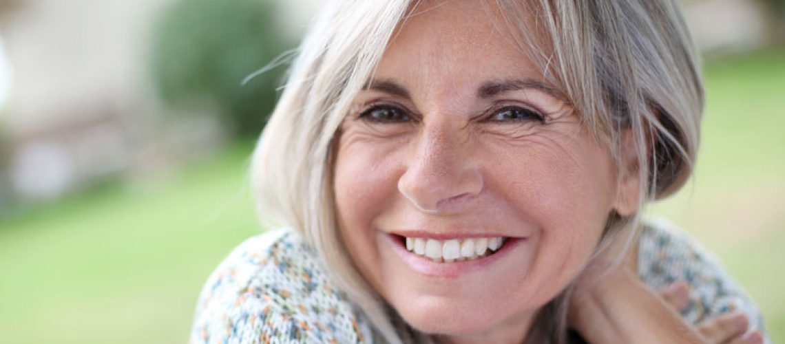 a dental patient outside smiling because she has false teeth