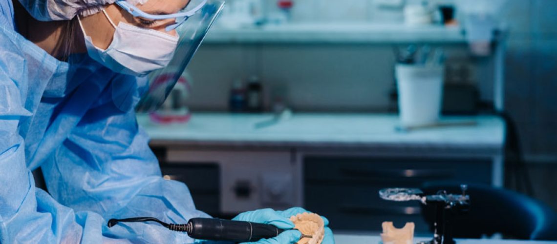 a dental implant dentist milling a full mouth dental implant prosthetic in a dental lab.